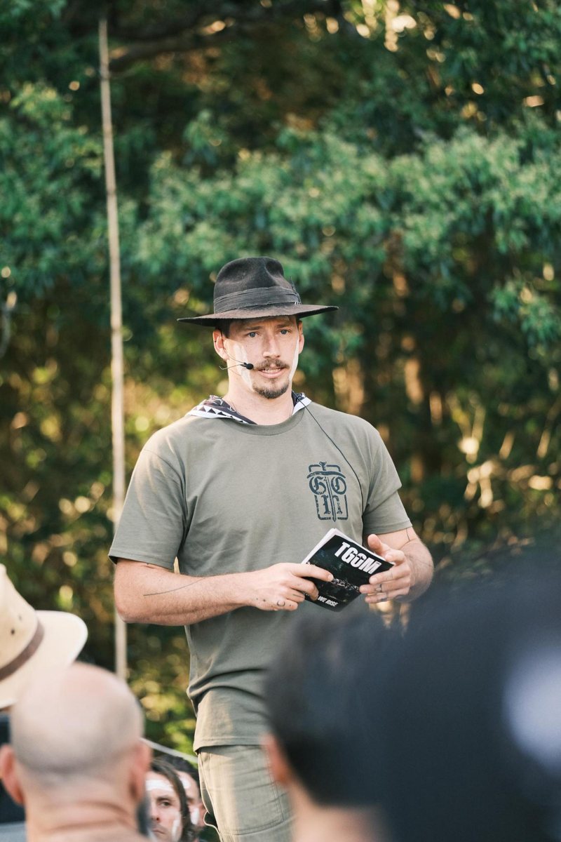 Ryan Barraclough in a black hat, speaking to a gathering of men