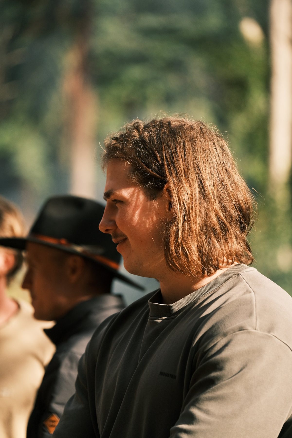 A young man in profile, smiling in the afternoon light