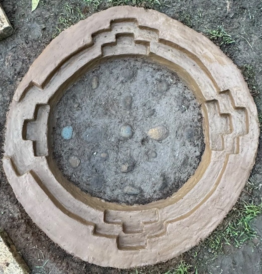 A clay fire pit shaped with stepped chakana patterns, seen from above