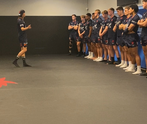 Velan speaking to a line of Sydney Roosters players in the team room