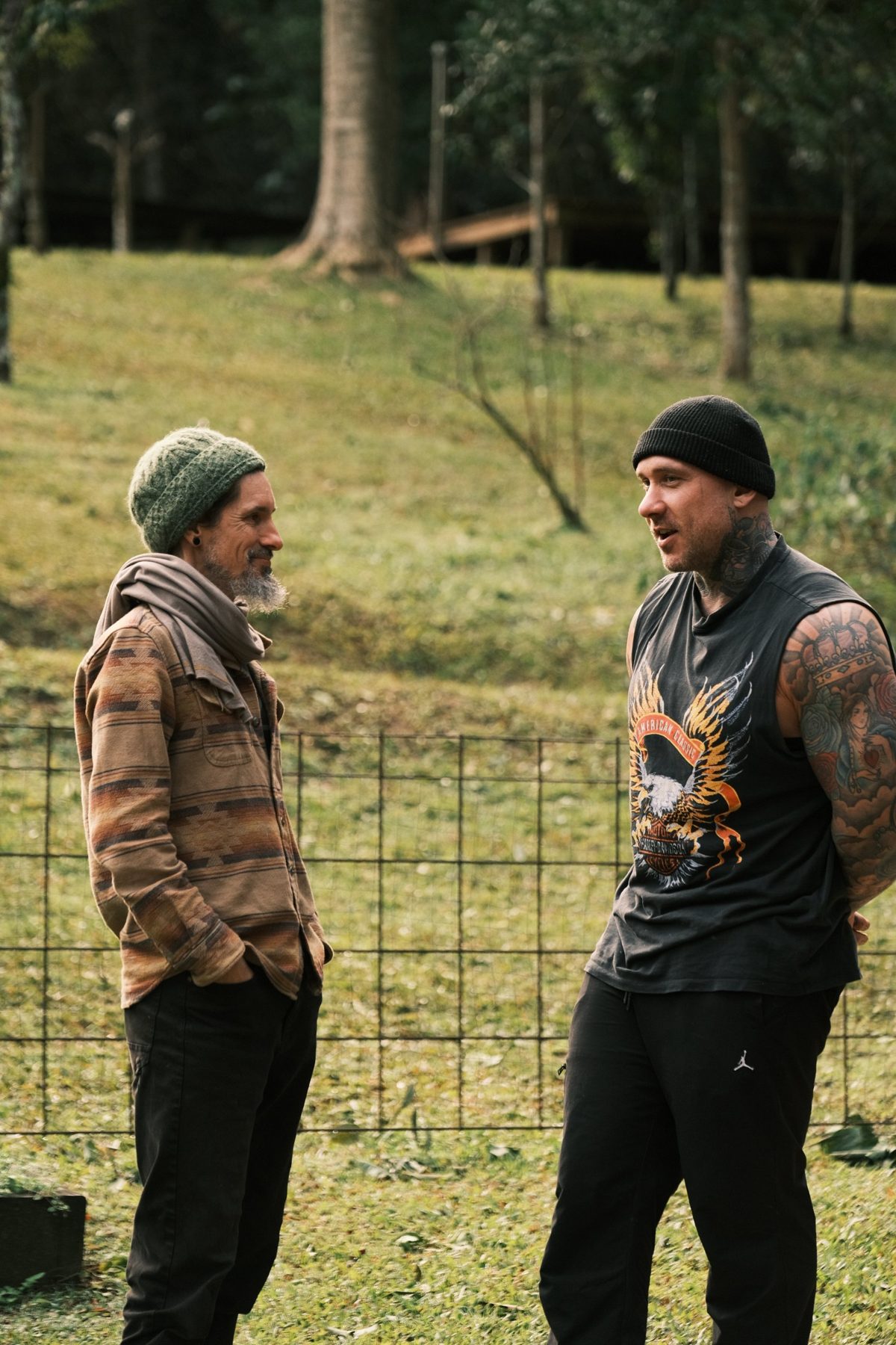 Velan in conversation with a tattooed man on the land